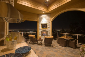 A patio with chairs and tables, fireplace and a view of the city.